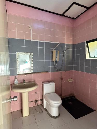 een roze badkamer met een toilet en een wastafel bij Arsahrin Motel Apartment 