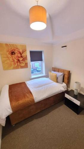 a bedroom with a large bed with a painting on the wall at 3-Bed House in Warrington in Warrington