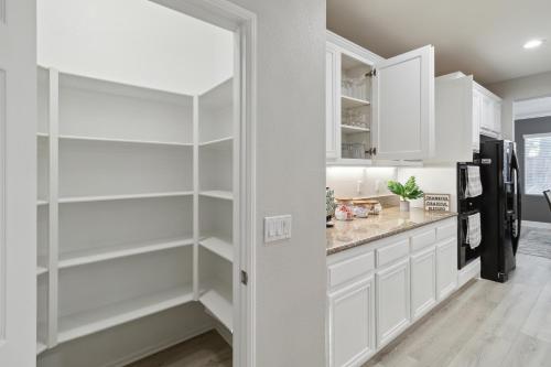 a kitchen with white cabinets and a refrigerator at 5BR 3BA Home - King Beds - Fast Wifi home in Victorville
