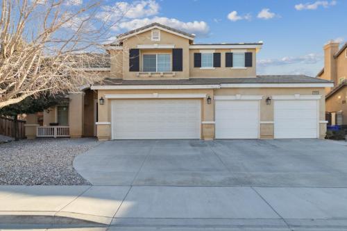 una casa con dos puertas de garaje en una entrada en 5BR 3BA Home - King Beds - Fast Wifi home en Victorville