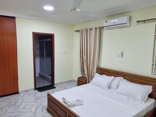 a bedroom with a large white bed and a mirror at B's Classic and Cozy Apartments in Cape Coast