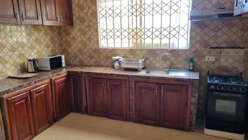 a kitchen with wooden cabinets and a sink and a window at B's Classic and Cozy Apartments in Cape Coast