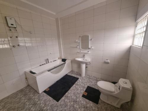 a bathroom with a tub and a toilet and a sink at B's Classic and Cozy Apartments in Cape Coast