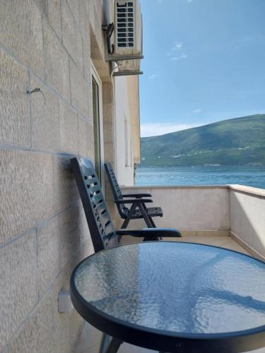 a table and chairs on a balcony with a view of the water at Apartments Villa Danilovic in Herceg-Novi