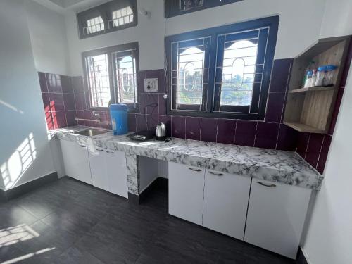 a kitchen with a counter and a sink and windows at BKR homestay 2bhk in Itānagar