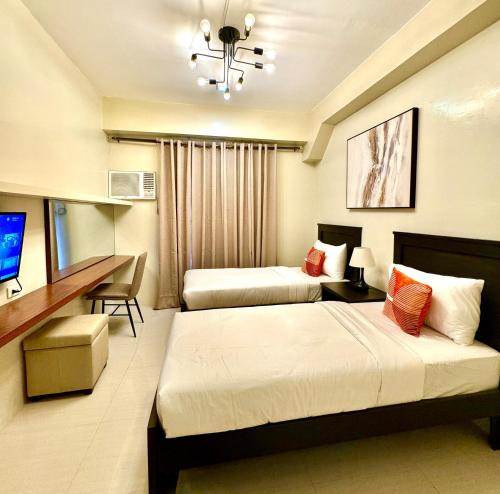 Habitación de hotel con 2 camas y escritorio en G Square Residences, en Manila