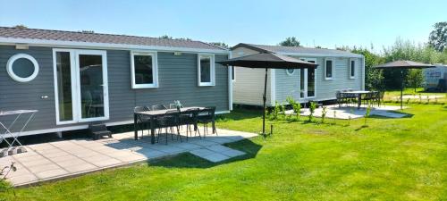 une maison avec une table, des chaises et un parasol dans l'établissement Mini Camping Het Schuttersplek, à Drogeham