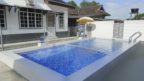 a swimming pool in front of a house at NAZZA Homestay Besut with Swimming Pool in Kampung Raja