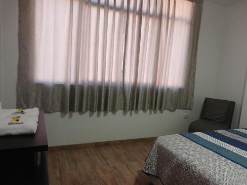 een slaapkamer met een bed en een raam met een stoel bij Hospedaje Margarita in La Merced