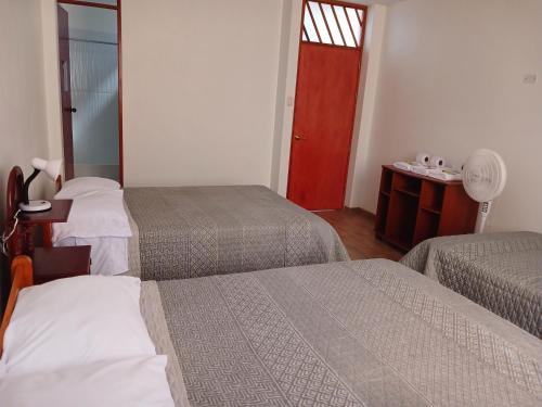 a hotel room with two beds and a red door at Hospedaje Margarita in La Merced