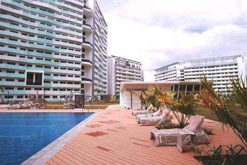 a swimming pool with lounge chairs and some buildings at Private condo w/ balcony near Batasan, Ateneo, UP, Diliman, The Residences at Commonwealth in Manila