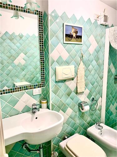 a green tiled bathroom with a sink and a toilet at LA DEPENDANCE in Su Forti