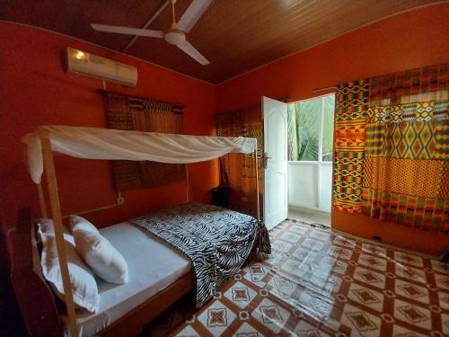 a bedroom with a bed in a room with orange walls at Orange Beach hostel in Cape Coast