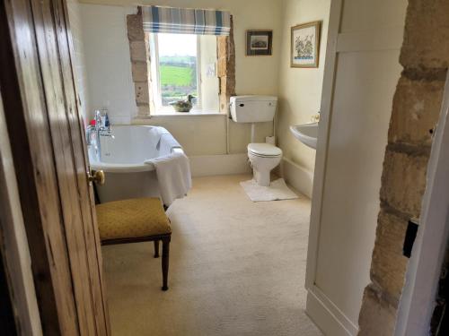 a bathroom with a tub and a toilet and a window at Prebendal Manor in Nassington