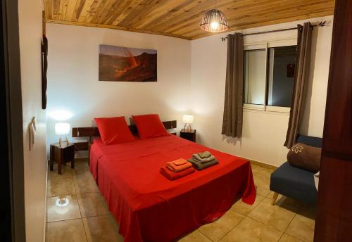 1 dormitorio con cama roja y sofá en Meublé de tourisme Makaze, en Saint-Louis