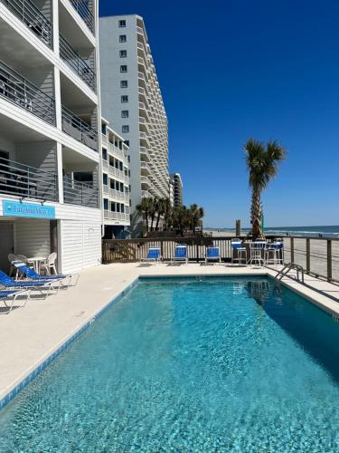 a swimming pool in front of a building and the ocean at Carolina Shores ll in Myrtle Beach