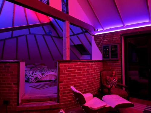 um quarto com uma cama e luzes roxas em Unique luxury self-contained oast apartment em Kent