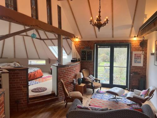 uma sala de estar com uma cama e uma parede de tijolos em Unique luxury self-contained oast apartment em Kent