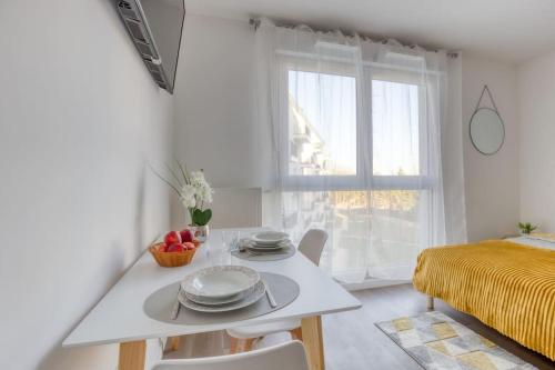 a white dining room with a table and a window at Escapade parisienne à 25 minutes de la Tour Eiffel in Villeneuve-la-Garenne