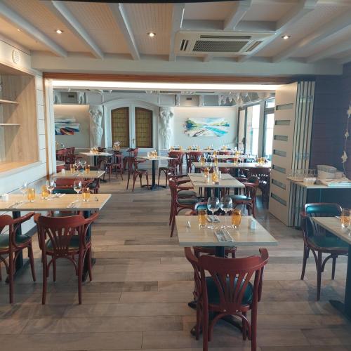 a dining room with tables and chairs and tablesktop at Logis Hotels - Au Poisson d'Argent - Hôtel 3 étoiles et restaurant in Le Mesnil-en-Vallée
