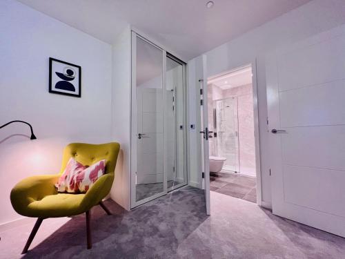 NEW Cosy 3BR Apartment With Private Garden In Olympic Park في لندن: حمام به كرسي اصفر ومرآة