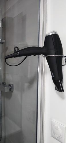 un sèche-cheveux noir suspendu à une porte en verre dans l'établissement Spacieux et serein avec patio, barbecue et WIFI, à Guebwiller