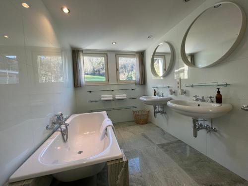 a bathroom with two sinks and two mirrors at Villa Rebgärtle mit Seeblick in Bregenz