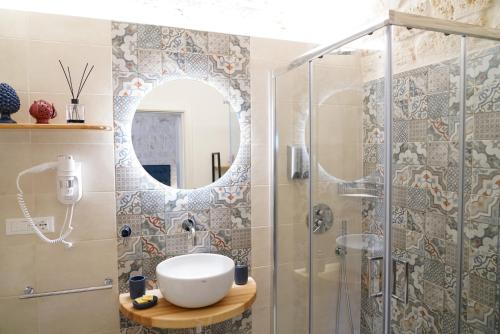 ein Bad mit einer Dusche, einem Waschbecken und einem Spiegel in der Unterkunft La Suite del Conte - STORIA, CONFORT ed ELEGANZA in Ceglie Messapica