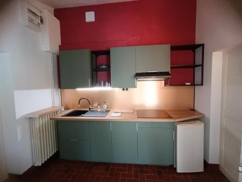 una cocina con armarios verdes y paredes rojas en Les gîtes des Beaux Chênes, en Mortagne-sur-Sèvre