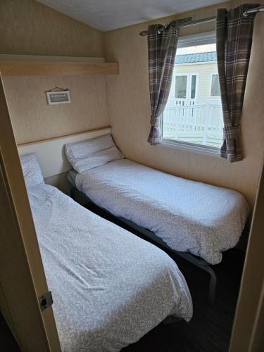 two beds in a small room with a window at 113 Caravan at meadow lakes in St Austell