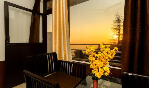 a table with a vase of yellow flowers on a balcony at Mirage Grand in McLeod Ganj