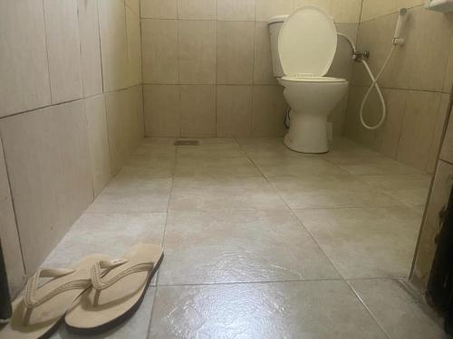 a bathroom with a toilet and a sandal on the floor at Retreat Homes in Dar es Salaam