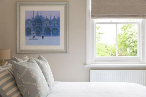 a white bedroom with a bed and a window at Stylish and homely 1 bed Edwardian Coach House in Colchester