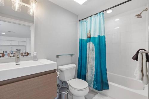 baño con aseo y cortina de ducha azul en Stone's Throw from Capitol Hill Free Parking, en Washington