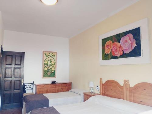 a bedroom with two beds and two paintings on the wall at Casa Olga in Caleta de Sebo