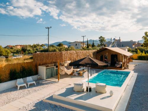 a swimming pool with a tent and chairs and a house at NOMAD GLAMPING in Schinias