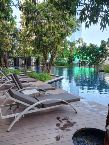 a row of lounge chairs sitting on a deck near the water at LUCENTIA KUALA LAMPUR in Kuala Lumpur