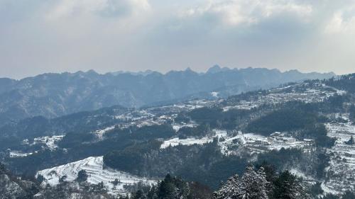 a view of a snowy mountain with trees and houses at Zhangjiajie National Park Nvue Resorts in Zhangjiajie