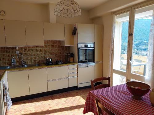 une cuisine avec des armoires blanches, une table et une fenêtre dans l'établissement Vue montagne et terrasse privée Appartement centre Nyons, à Nyons