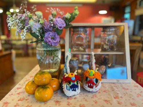 a table with oranges and a vase with flowers at DeerStar HomeStay B&B in Dongshan
