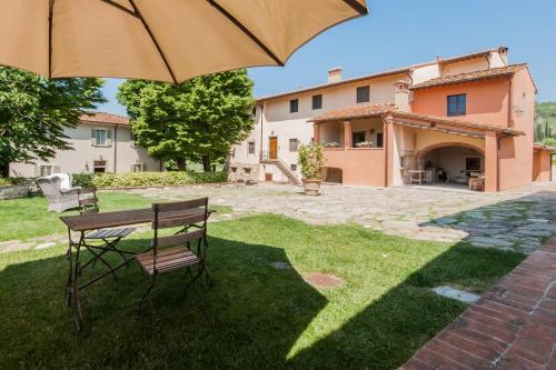 a patio with a table and a chair and an umbrella at Borgo I Vicelli Adults Only Relais in Bagno a Ripoli