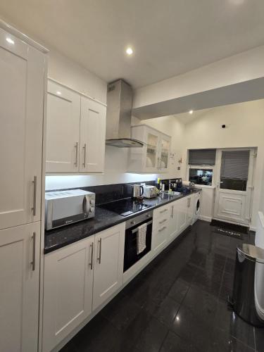 a kitchen with white cabinets and black counter tops at 38 Church Street Luxury Flat in Warrington
