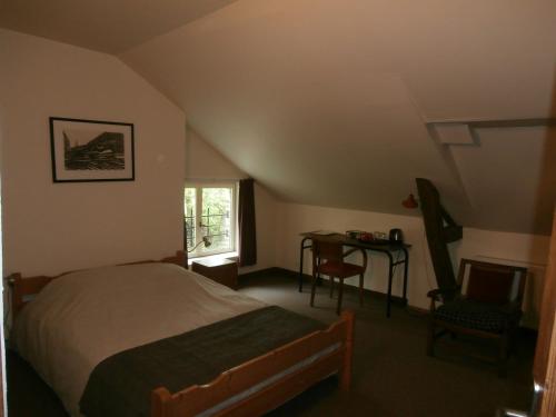 1 dormitorio con cama, escritorio y ventana en Chambre d'hôtes L'Ermite en Saint-Algis
