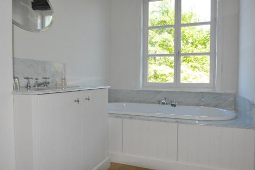 a white bathroom with a tub and a window at B & B Landhuis Ter Velt in Melle