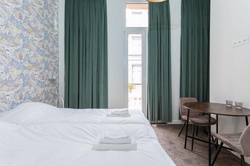 Van Lerius room في أنتويرب: غرفة نوم بسرير وطاولة وستائر خضراء