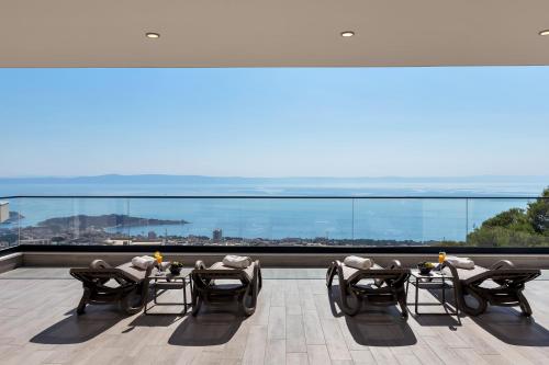 a balcony with chairs and tables and a view of the city at Luxury Villa Bašak with Infinity Pool and Sea View in Makarska