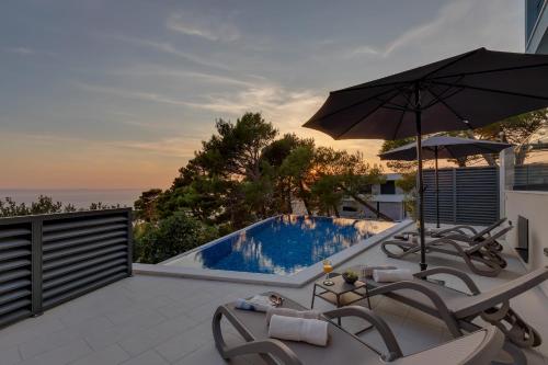a pool with chairs and an umbrella on a patio at Luxury Villa Bašak with Infinity Pool and Sea View in Makarska