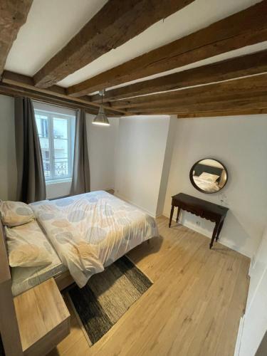 a bedroom with a bed and a mirror and a table at Charmant appartement Orléans ! in Orléans