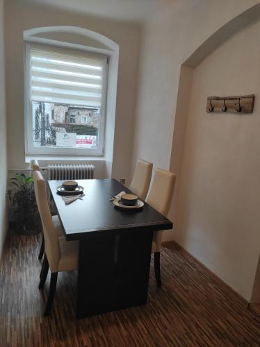 a dining room with a table and chairs and a window at Apartmán U Krtka in Lázně Kynžvart