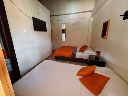 a small room with two beds and a television at Hostal Casa de Vicente in Salento